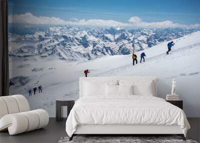 A group of people walking on the snowy mountains with their snowshoes on. Climbing the icy mountains Wall mural