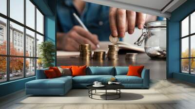 business accounting with saving money with hand putting coins in jug glass concept financial. Wall mural