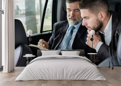 business colleagues discussing business ideas while sitting in backseat of the car or taxi. Wall mural