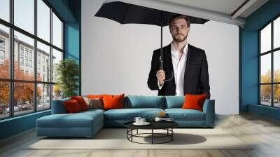 Businessman in a suit standing under black umbrella Wall mural