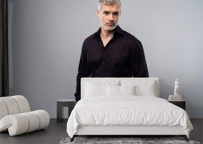 Cheerful man of middle age against white background, wearing jeans and black shirt, mid shot. Wall mural