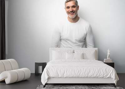 Cheerful man of middle age against white background, wearing jeans and white T-shirt, mid shot. Wall mural