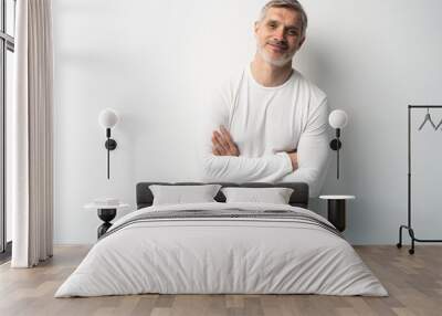 Cheerful man of middle age against white background, wearing jeans and white T-shirt, mid shot. Wall mural