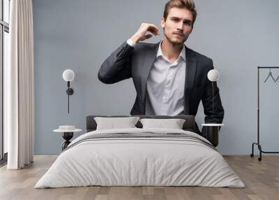 Close up portrait of a handsome young businessman dressed in suit isolated over gray background, looking away. Wall mural