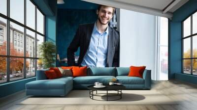 Confident professional handsome businessman standing near window in his office Wall mural