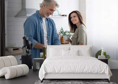 Couple cooking together in their kitchen at home. Wall mural