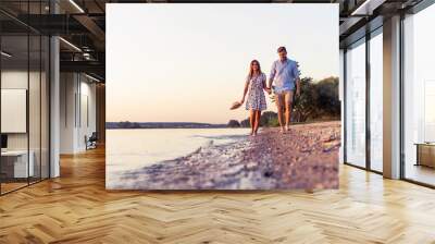 Couple walking on the beach at sunset Wall mural