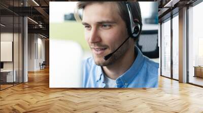 Dedicated service creates dedicated customers. Shot of a young man using a headset and computer in a modern office Wall mural