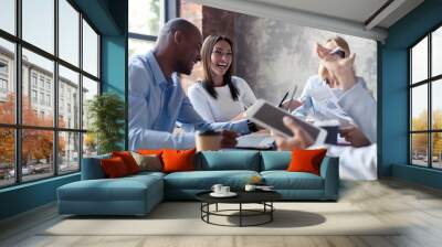 Full concentration at work. Group of young business people working and communicating while sitting at the office desk together with colleagues sitting in the background. Wall mural