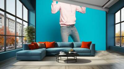 Full length of a cheerful young man standing and celebrating success isolated over light blue background. Wall mural