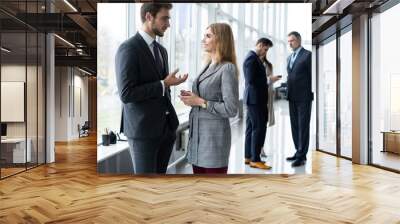 group of modern business people chatting during coffee break standing in sunlit glass hall of office Wall mural