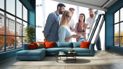 Group of young colleagues dressed casual standing together in modern office and brainstorming. Wall mural