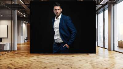 Handsome man wear blue suit isolated on black background Wall mural