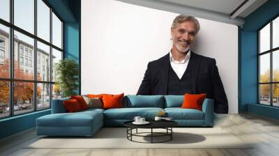 Handsome smiling middle-aged man in suit posing against grey background Wall mural