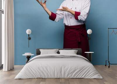 Happy male chef cook standing with plate isolated on light blue background. Wall mural