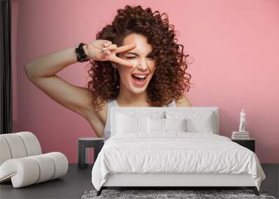 image of happy young woman standing isolated over pink background showing peace gesture. looking cam Wall mural