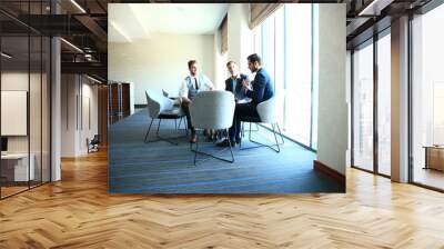 mature businessman using a digital tablet to discuss information with a younger colleague in a moder Wall mural