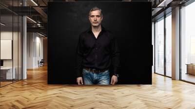 Middle-aged good looking man posing in front of a black background with copy space. Wall mural