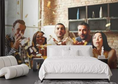 Party fun. Group of beautiful young people throwing colorful confetti and looking happy. Wall mural