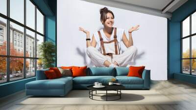 Portrait of a casual happy woman sitting on the floor on white background. Wall mural