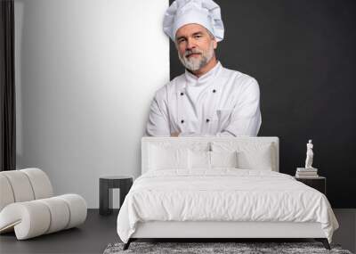 Portrait of a happy mature chef cook showing copyspace on the palms isolated on black background. Wall mural