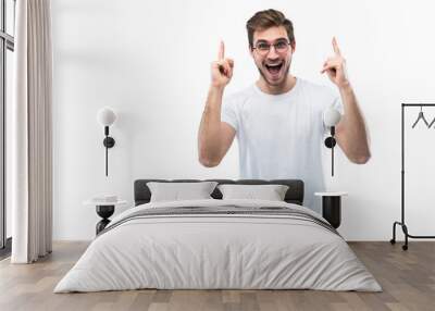 Portrait of a happy young man pointing fingers up at copy space isolated over transparent background Wall mural