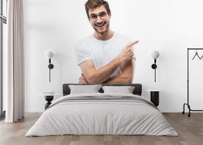 Portrait of a joyful young man pointing fingers away at copy space on his palm isolated over transparent background Wall mural