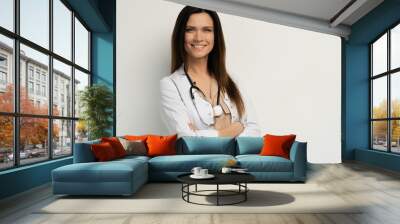 Portrait of an attractive young female doctor in white coat. Wall mural