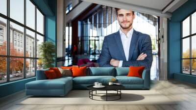 Portrait of happy businessman with arms crossed standing in office. Wall mural