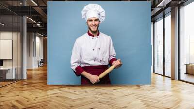 Portrait of positive toothy chef cook in beret, white outfit having tools in crossed arms looking at camera. Wall mural