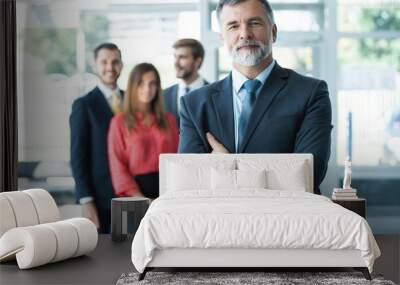 Proud smiling businessman standing with his colleagues at office Wall mural