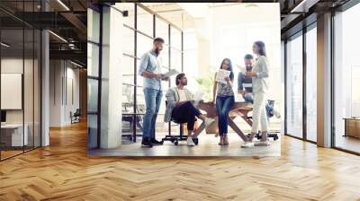 Sharing fresh ideas. Group of young business people in smart casual wear talking and smiling in the office hallway. Wall mural