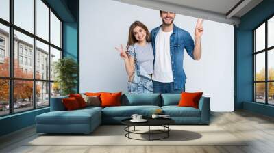 smiling young casual couple making victory or peace sign on white background. Wall mural