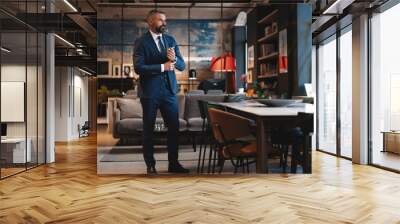 Stylish bearded man in a suit standing in modern office Wall mural