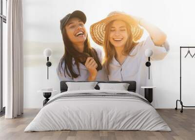 Two beautiful young women strolling on a beach. Female friends walking on the beach and laughing on a summer day. Wall mural