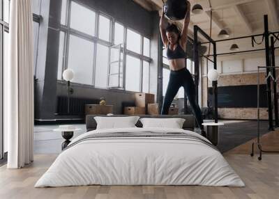 Woman doing exercise with heavy medicine ball in gym. Wall mural