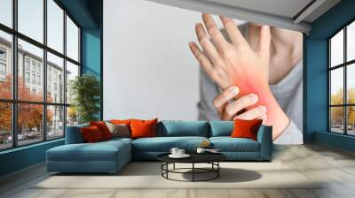 Close-up of a person holding a wrist in pain. Highlighted red area depicting inflammation or injury. Concept of joint pain, arthritis, and health issues. Wall mural