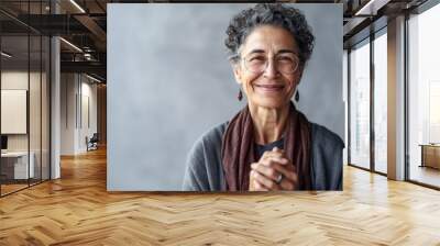 60 year old smiling woman in front of a grey wall. Generative AI. Wall mural