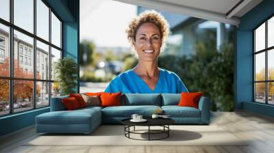 A nurse posing outdoors in summer sun in front of a hospital. Wall mural