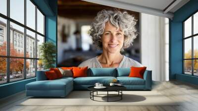 Middle age woman with curly grey hair in casual clothing posing at home. Wall mural