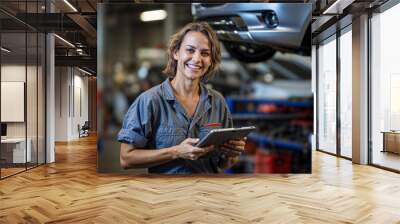 Woman car mechanic working with a tablet in an automobile garage, car repair workshop maintenance and service, smiling proud female Wall mural