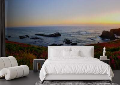 Scenic panorama shot of a seacoast with beautiful flowers and a lighthouse at sunset Wall mural