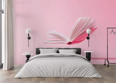 An open book floating in mid-air against a pink background. Wall mural