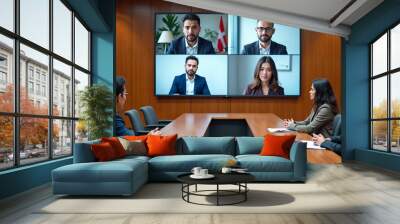 A conference room with a large wooden table, one Asian male participant sitting at the end, and an African female participant on the left. On the wall, a large screen shows video feeds of five people Wall mural