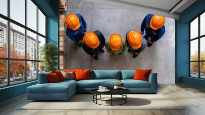 Group of workers in safety helmets collaborating in a warehouse. Wall mural