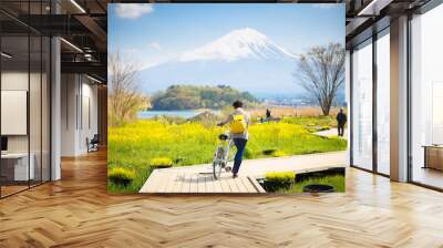 Mountai fuji with snow and flower garden along the wooden bridge at Kawaguchiko lake in japan, Mt Fuji is one of famous place in Japan. A women take a bicycle on wooden bridge. Wall mural