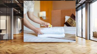 A hotel maid stacked towels on the bed and placed flowers on the towels in a hotel room Wall mural