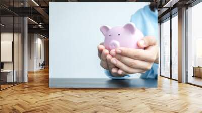 A woman's hand holds a piggy bank for saving into a growing business to succeed and save for retirement Wall mural