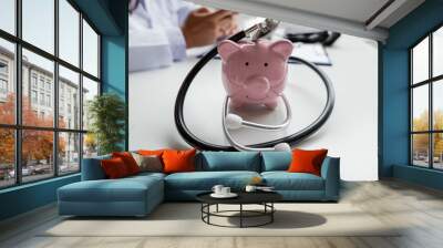 Pink piggy bank with medical equipment on a white table and nurse sitting behind Medical concepts and health insurance Wall mural