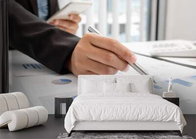 The hands of a male businesswoman are analyzing and calculating the annual income and expenses in a financial graph that shows results To summarize balances overall in office Wall mural